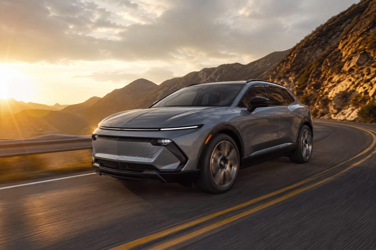 Chevy electric car SUV cornering on winding mountain road at dusk